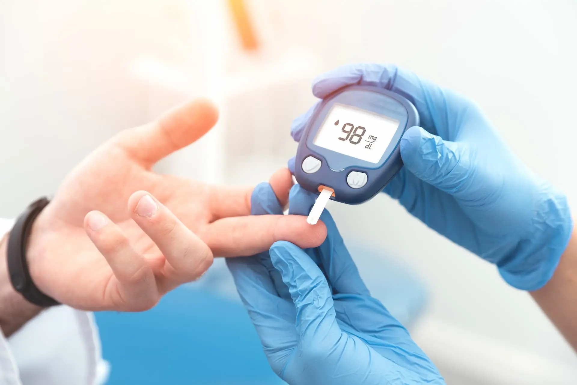 Clinician measuring a professional's blood glucose — 98 mg/dL reading